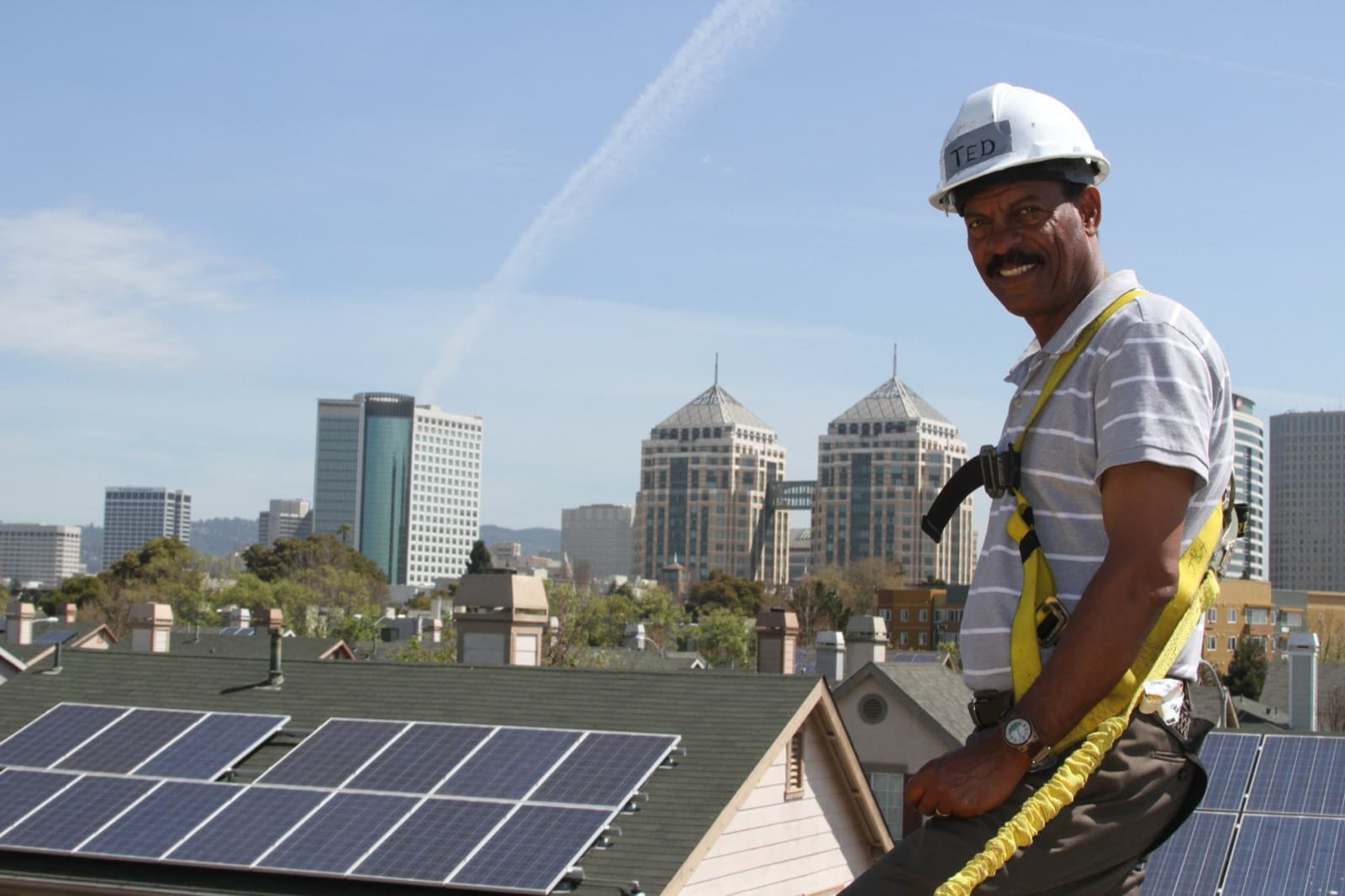 Solar installer in a harness working on a residential shingle roof